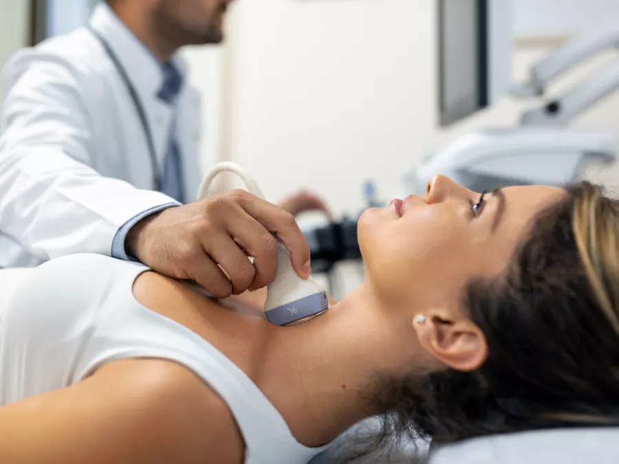 Close up shot young woman getting her neck examined by doctor using ultrasound scanner modern clinic